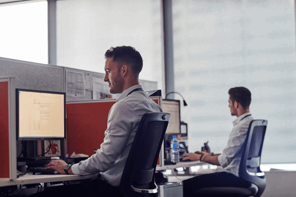 two people sitting at computers in an office